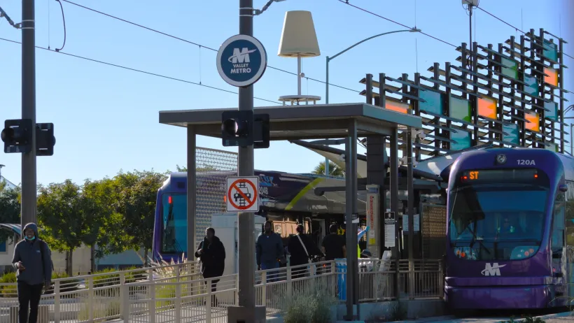 Purple Phoenix light rail car at station with decorative glass panels.