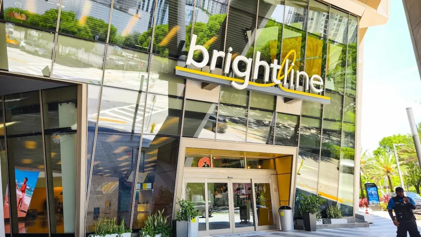 The outside of a brightline transit hub with many windows on a sunny day.