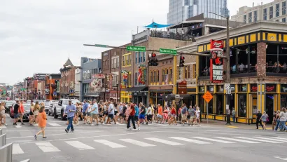 Crowd of people in crosswalk on busy street in downtown Nashville, Tennessee.