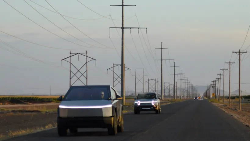Two silver Cybertrucks driving down rural road with fog,