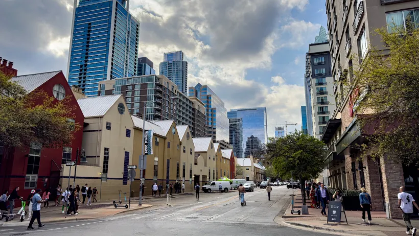 Street with two-story apartment buildings in Austin, Texas with downtown skyline visible in background.