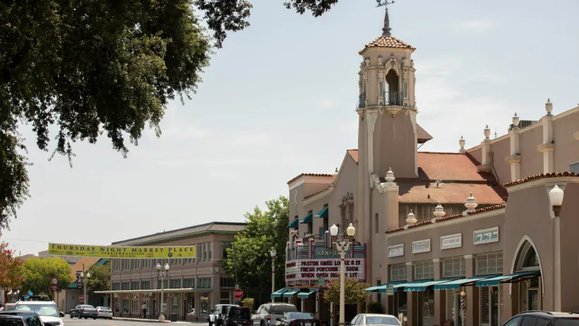 Street in Hanford, California with old Spanish-style church with tall steeple and cinema-style marquee.