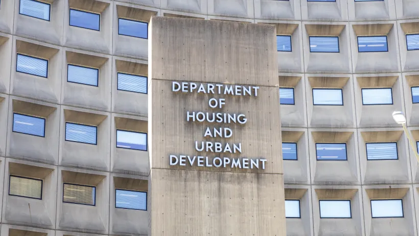 The Department of Housing and Urban Development Building sign. The cement sign is flanked on either side by rows of windows.