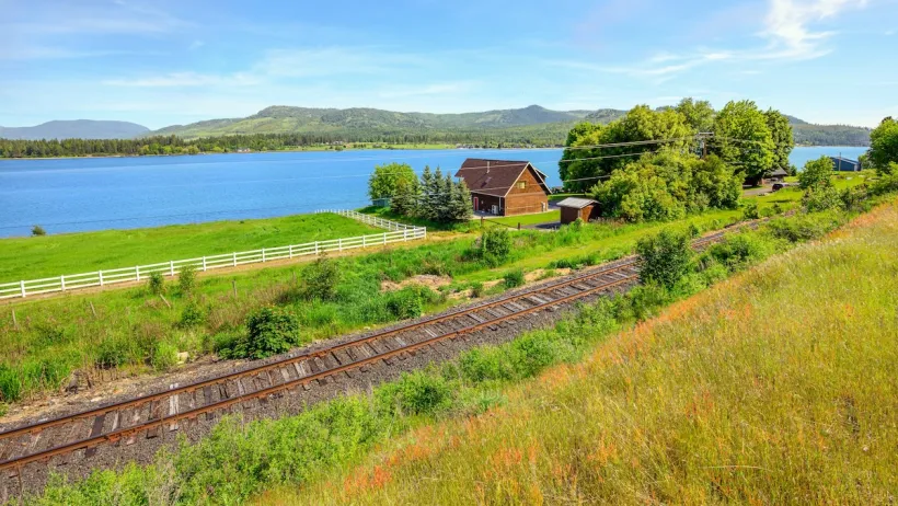 Railroad tracks in Idaho passing a home by a river.