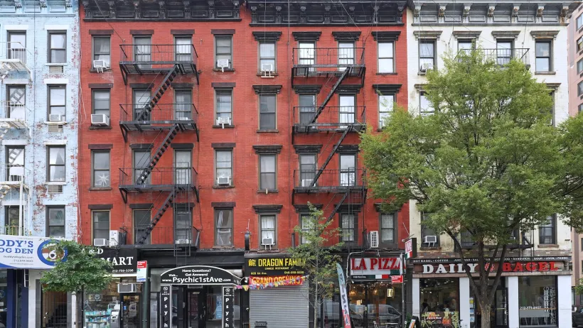 Brick New York City apartment buildings with commercial businesses on ground floor.
