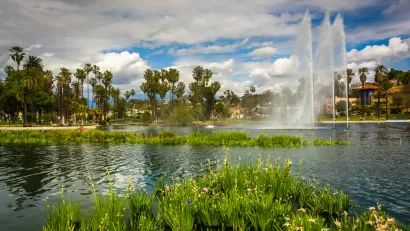 Echo Park Lake with tall artesian fountain, palm trees and apartment buildings in background.