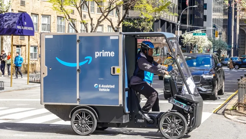 A blue Amazon three-wheeled electric delivery cargo bike in New York City.