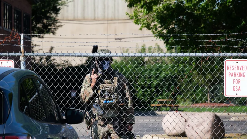 Armed guard standing behind fence at Chicago ICE detention facilities.