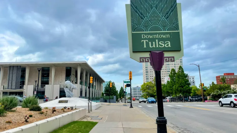Downtown Tulsa sign and street view with the Tulsa Performing Arts Center under stormy skies.