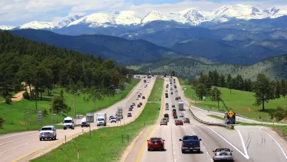 Cars on highway in Colorado with snow-capped mountains in background