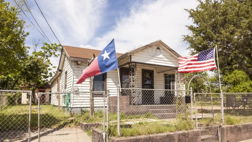 Small home with Texas and USA flags in front yard.