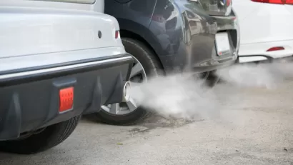 Close-up of back of three cars in a line with smoke coming from tailpipes