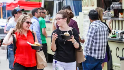 Food truck customers holding food with food trucks in background