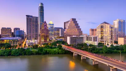 View of Austin, Texas skyline at dusk with Colorado River and bridge in foreground
