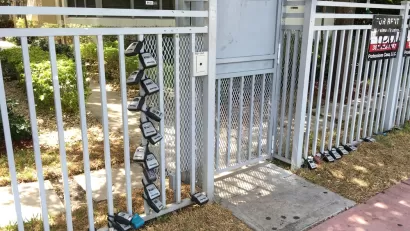 Gate in front of Miami Beach apartment building with many lock boxes for short-term renter access