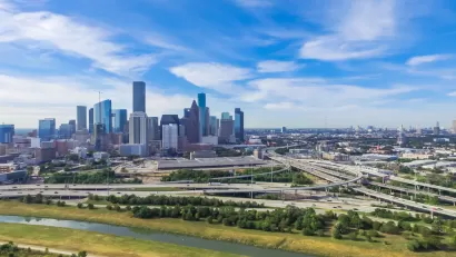 View of Houston freeways and downtown skyline in the background against blue sky with white clouds