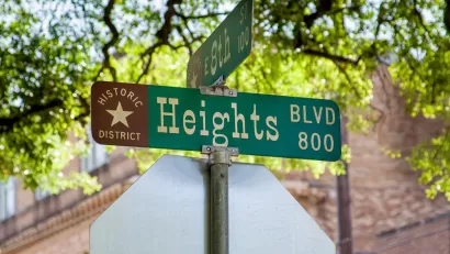 Close-up of green street sign at Heights Blvd and 8th Street in Houston, Texas with "Historic District" and star logo
