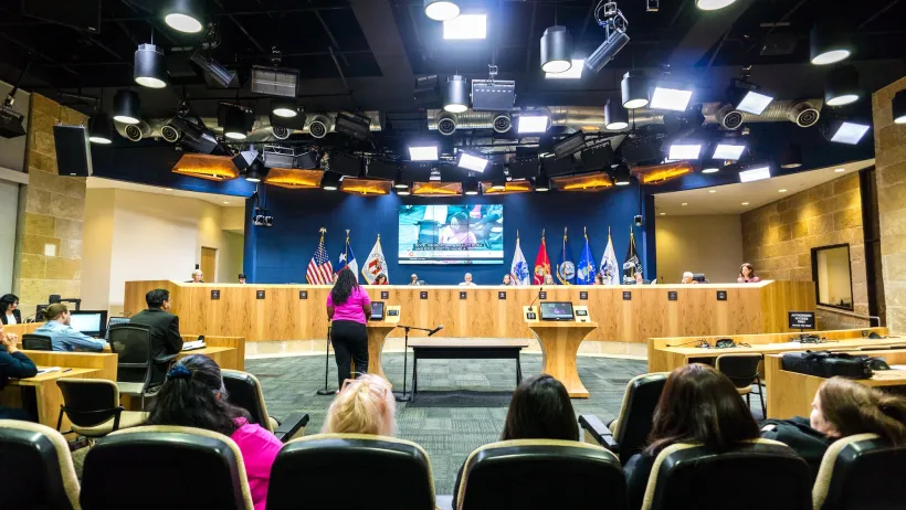Person stands at podium to speak to city council or committee in government building in Austin, Texas.