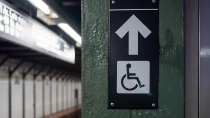 Accessible elevator sign with arrow on a New York City subway platform
