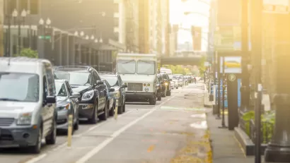 Bike lane and line of cars on street in Chicago with sun in background
