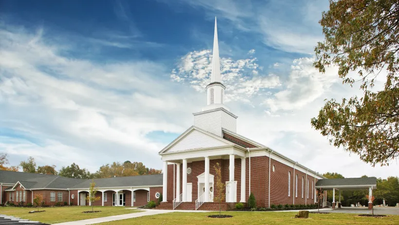 Traditional small brick church with tall white steeple in Virginia.