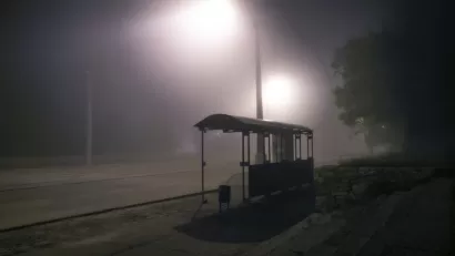 Bus shelter from behind at night with mist and streetlights