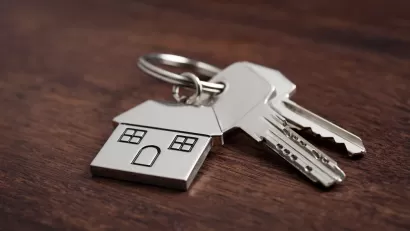 House key with house-shaped keychain on table
