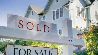 White house with For Sale and SOLD sign