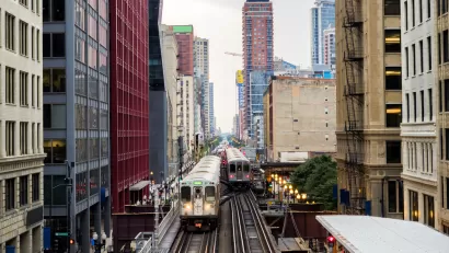 Two Chicago elevated trains with city buildings in background