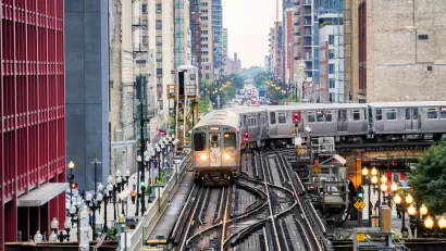Chicago elevated train over busy city street surrounded by high-rise buildings