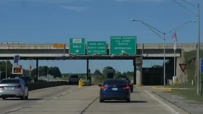 View of cars on Oklahoma road with green signs signaling tolls ahead
