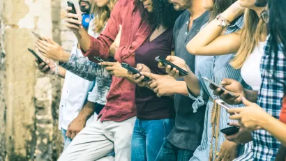 A row of young people outdoors using smartphones