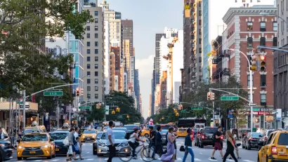 Pedestrians crossing a busy crosswalk on New York City street with tall buildings in background