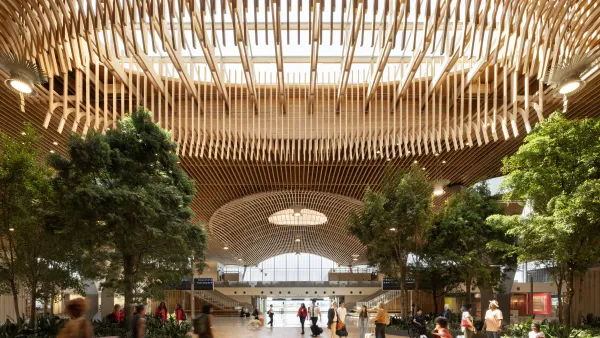 Indoor view of PDX's new massive airport terminal with a wooden beamed roof and skylight.