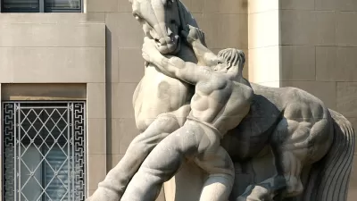 A stone statue of a shirtless muscular man wrestling with a powerfully built horse, his hands on the horse's neck, pulling downward.
