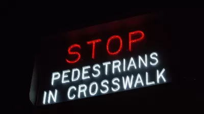 "Stop - Pedestrians in crosswalk" sign in white and red lights.