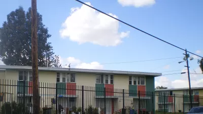 Two-story apartment building behind black iron fence in Pacoima, California