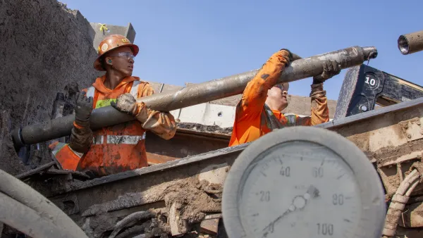 Worker in orange safety jacket working on California high-speed rail infrastructure.