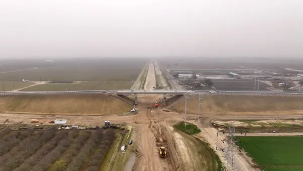 Construction for California's high-speed rail line. A concrete bridge stretches over a dirt field. 