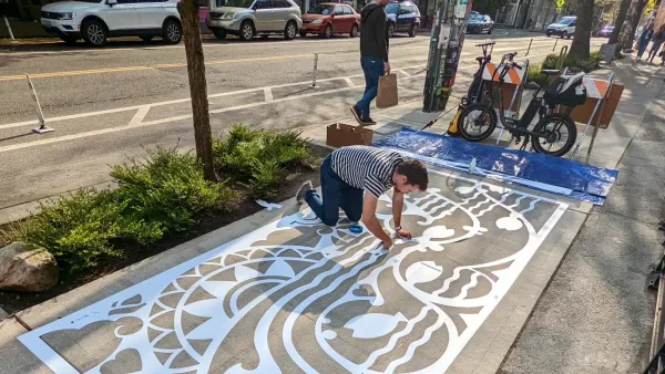 Man stenciling sidewalk with large stencil of water-activated paint in Seattle, Washington.