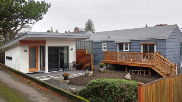 White accessory dwelling unit in backyard of small grey home in Seattle, Washington.