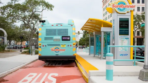 Light teal SunRunner transit bus in St. Petersburg, Florida parked at station on red painted bus lane.