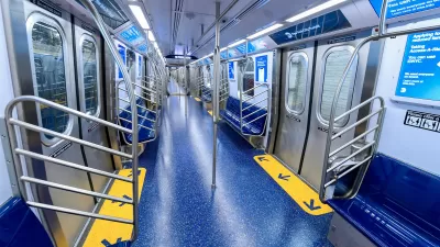 Interior of a subway car with wide doors and blue floors and seats.
