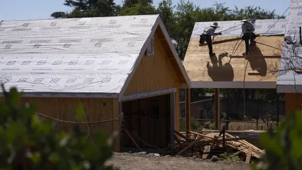 Two workers on roof of house under construction in Altadena, California with other house under construction next to it.