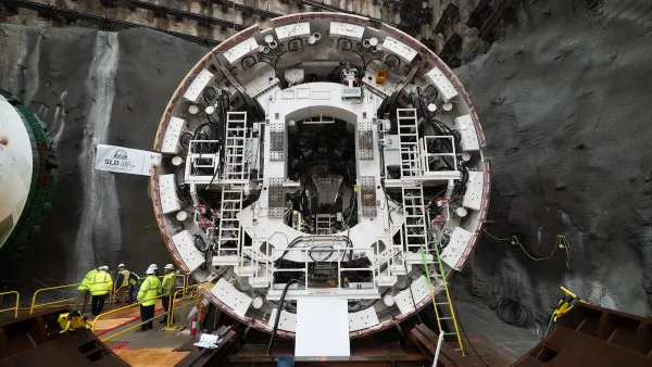 The tunnel-boring machine, a circular drill manned by people in high-vis yellow jackets.