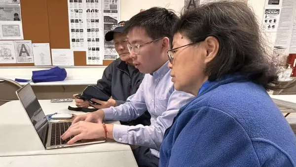 Young Chinese American man helping two seniors sign up for services on a laptop.