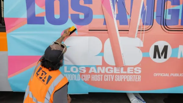A metro worker wraps an LA Metro bus in wrap celebrating the FIFA World Cup.