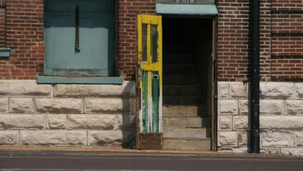 Open door leading to stairway in urban brick building.