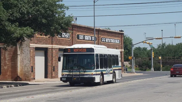 White transit bus in Abilene, Texas passing by brick buildings.
