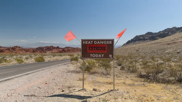 "Heat Danger Extreme Today" sign on desert roadside with orange flags on either side.